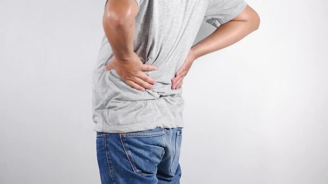 Men experience lower back pain, acute back pain, holding their spine in discomfort due to lower back pain. A stiff posture indicates spinal tension and physical stress.