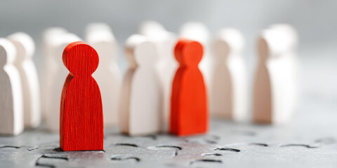 Red Wooden Figure Symbolizing Human Resources Stands Out Amidst White Figures on Puzzle Background in Job Interview Setting