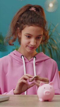 Caucasian preteen girl putting one dollar cash money into piggy bank. Young school child enjoying her first saving at home workplace sitting at the table. Kids and financial literacy budget planning