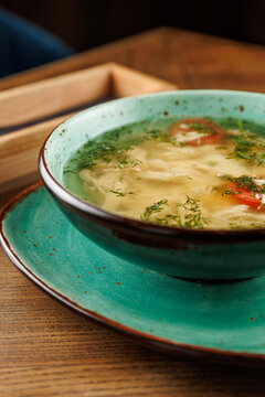 Warm bowl of chicken soup with herbs and vegetables served in a blue dish at a cozy restaurant in the afternoon
