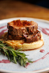 Delicious beef tenderloin served over creamy mashed potatoes with a red wine reduction and a sprig...