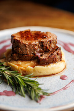 Delicious beef tenderloin served over creamy mashed potatoes with a red wine reduction and a sprig of rosemary on the plate