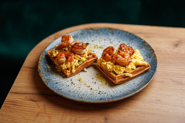 Savory shrimp and scrambled eggs served on crispy waffles at a restaurant