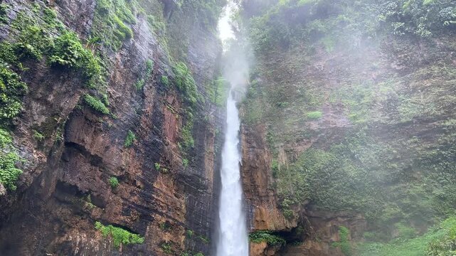 Koban Kapas Biru is a waterfall in the tropical jungles of East Java, descending from a high cliff into a lush green canyon surrounded by tropical forests with vibrant vegetation.Lumajang River. 4К
