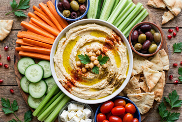 A vibrant and fresh hummus platter with assorted vegetables and pita bread.
