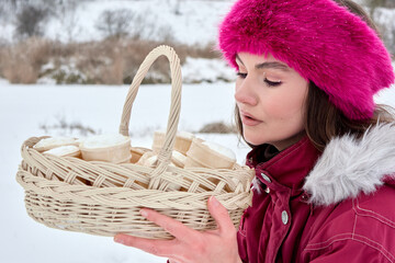 A stunning woman in a stylish pink fur hat presents a basket of ice cream cones against a tranquil...