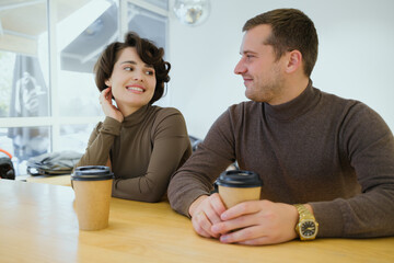 Casual couple enjoying coffee together at a bright cafe, smiling and sharing a light conversation