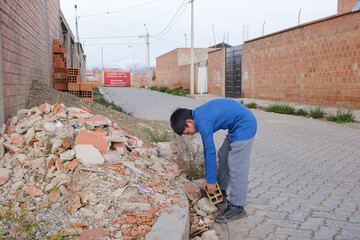 Latino child working, carrying bricks and rubble in the streets of Bolivia - concept of work