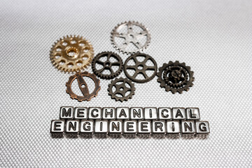 Concept of Mechanical Engineering, created with text on beads and cog wheels on metallic background.