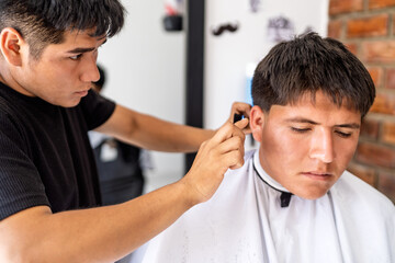 Barber carefully trimming customer hair in barbershop