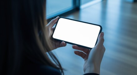 Woman holds blank smartphone in landscape mode, ideal for app promotion or mobile content mockups