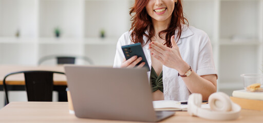 Focused busy caucasian businesswoman in a beige blazer sits at a modern office desk using her...
