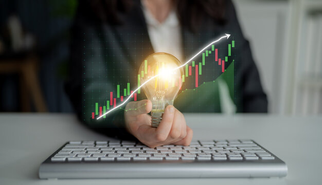 A light bulb symbolizes inspiration and creativity in front of a keyboard, with a graph demonstrating growth and innovation in the modern business workspace. Impute - Powered by Adobe