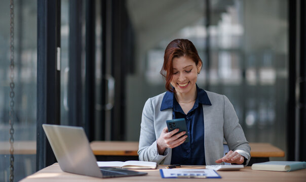 Business woman or accountant working online at office, laughing, using a phone and internet. Highlighting happiness, productivity, and the role of an accountant in a remote work setting.

