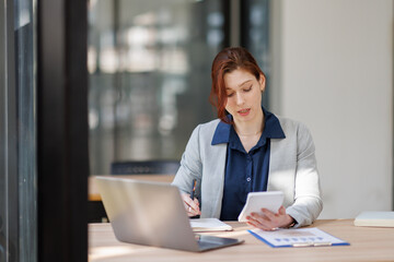 Business woman or accountant using calculator calculate while working analytic business report on the workplace, Planning financial and accounting concept.
