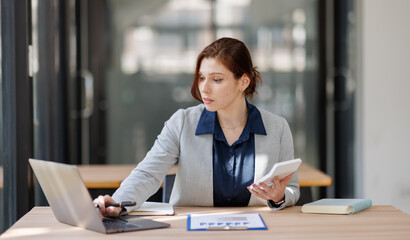 Business woman or accountant using calculator calculate while working analytic business report on the workplace, Planning financial and accounting concept.
