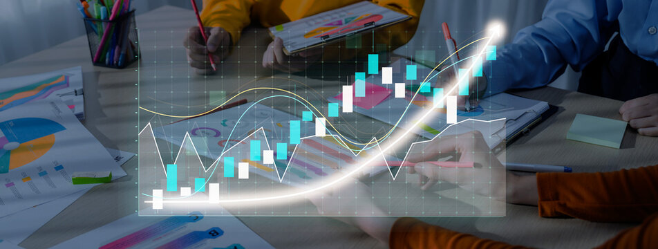 A focused business team collaborates on stock market analysis using digital tools, showcasing financial charts and graphs to strategize and visualize data trends effectively. Axiom - Powered by Adobe