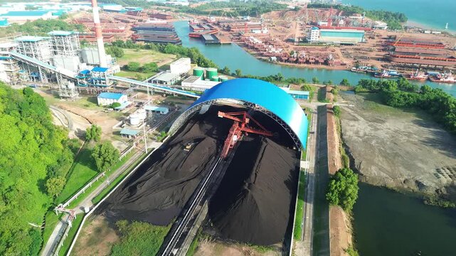 A vast energy logistics panorama with covered coal storage, integrated power plants and bustling activity.