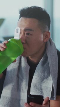 Man enjoys post exercise moment, Cheerful Asian male displays his workout success during casual gym session