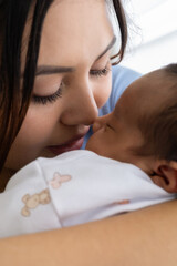 Intimate moment of a mother kissing her baby, symbolizing parental love, trust, warmth, and emotional attachment at home.