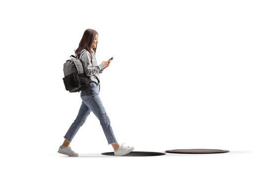Distracted female student walking with a mobile phone about to fall in an open manhole