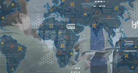 Discussing four-person team in blazers reviewing booklet in meeting room, with world-map overlay