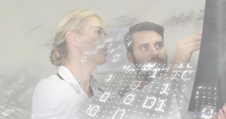 Pointing doctor explaining monitor in clinic while peer in lab coat listening, with binary overlay