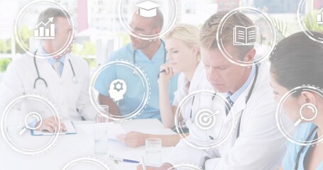 Discussing five staff in lab coats and scrubs reviewing charts at clinic with stethoscopes, icons