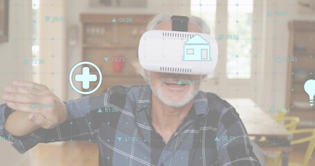 Reaching senior in plaid shirt wearing white VR-headset using VR interface home with medical icons