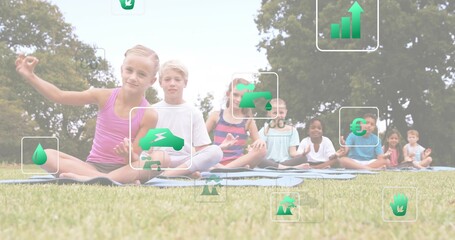Sitting eight children doing yoga on grassy field, in summer clothes, with mats and green icons