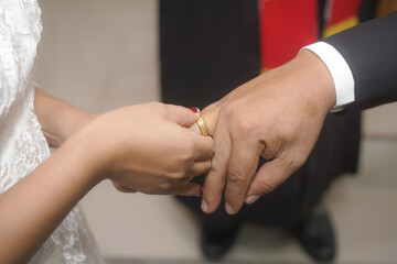 Bride placing wedding ring on groom's finger during ceremony