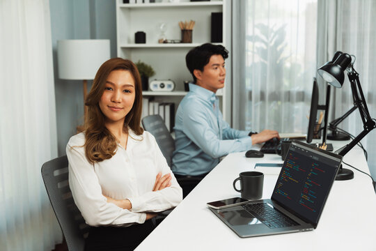 Profile smiling beautiful Asian businesswoman looking camera to portrait pose at modern office on working desk casual day. Blurry background man colleague analyzing data market plan on pc. Infobahn. - Powered by Adobe
