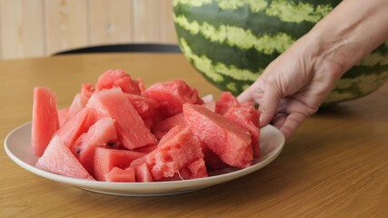 Preparing ripe watermelon at home is simple culinary experience Fresh watermelon cubes are refreshing fruit snack for hot season Video of watermelon preparation process creates natural summer mood - Powered by Adobe