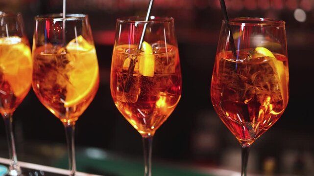 Bartender working, beautiful row line of different coloured liquor alcohol cocktails on a party in a bar, catering banquet on event, barman mixing drinks, selection of beverages in a restaurant club