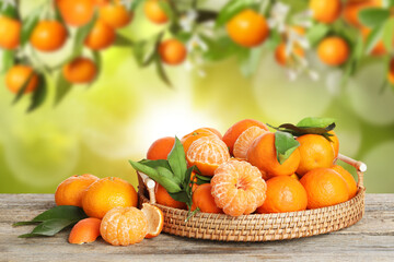 Fresh juicy tangerines in wicker tray on wooden table outdoors