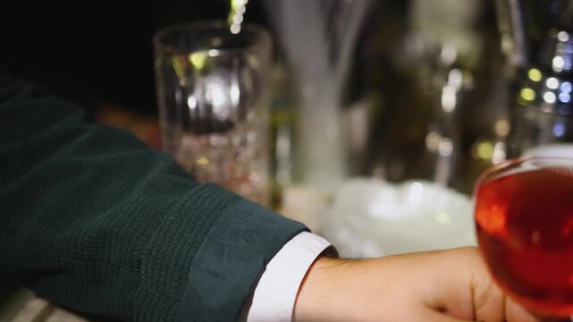 Bartender working, beautiful row line of different coloured liquor alcohol cocktails on a party in a bar, catering banquet on event, barman mixing drinks, selection of beverages in a restaurant club