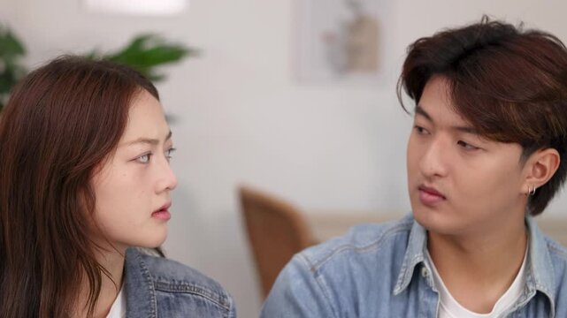 Young Asian Couple Having a Serious Conversation in a Modern Cafe