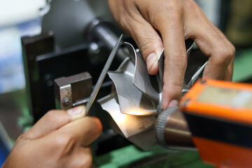 Close up of a technician's hands using a precision file on a turbocharger turbine wheel, professional metalworking and manual balancing for mechanical engine repair service.
