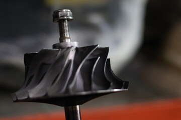 Close up of a damaged metallic turbocharger turbine wheel with broken blades, showing signs of...