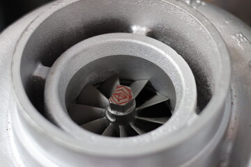Close up of a silver metallic turbocharger air intake housing and internal turbine wheel,...