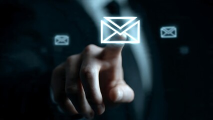 Professional businessman's hand reaching out to touch glowing digital envelope interface for modern communication and connectivity concept