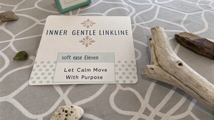 Inner Gentle Linkline Card displayed on neutral textured surface with pebbles and driftwood for a calming atmosphere