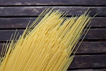 Raw pasta on wooden background. Uncooked spaghetti on a wood background. Pasta and food nutrition. Noodles recipes and cooking spaghetti.