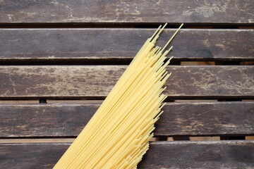 Raw pasta on wooden background. Uncooked spaghetti on a wood background. Pasta and food nutrition. Noodles recipes and cooking spaghetti.