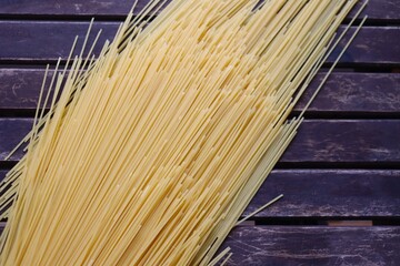 Raw pasta on wooden background. Uncooked spaghetti on a wood background. Pasta and food nutrition. Noodles recipes and cooking spaghetti.	
