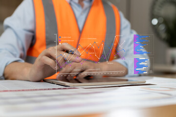 Engineer wearing safety vest analyzing construction project data with digital charts and graphs. Business analytics, performance metrics, planning, technology modern industrial management concept.