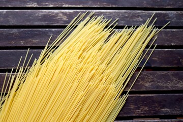 Raw pasta on wooden background. Uncooked spaghetti on a wood background. Pasta and food nutrition. Noodles recipes and cooking spaghetti.