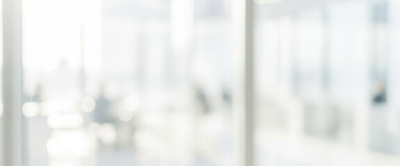 Bright and modern office interior filled with natural light. Blurred figures can be seen engaged in discussion or work, creating a dynamic and collaborative atmosphere.