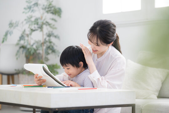 母親（ママ）に見守られながら、ノートを開いて学びを楽しむ幼児　お絵描きや塗り絵など一緒に楽しむ 子どもを褒める母親　やり抜く力の非認知能力を育む