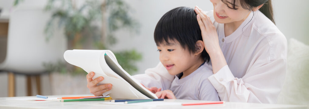 母親（ママ）に見守られながら、ノートを開いて学びを楽しむ幼児　お絵描きや塗り絵など一緒に楽しむ 子どもを褒める母親　やり抜く力の非認知能力を育む